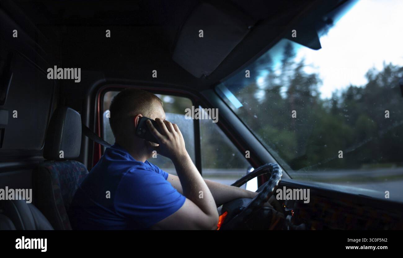 Man on phone while driving van during dusk, focused expression Stock Photo