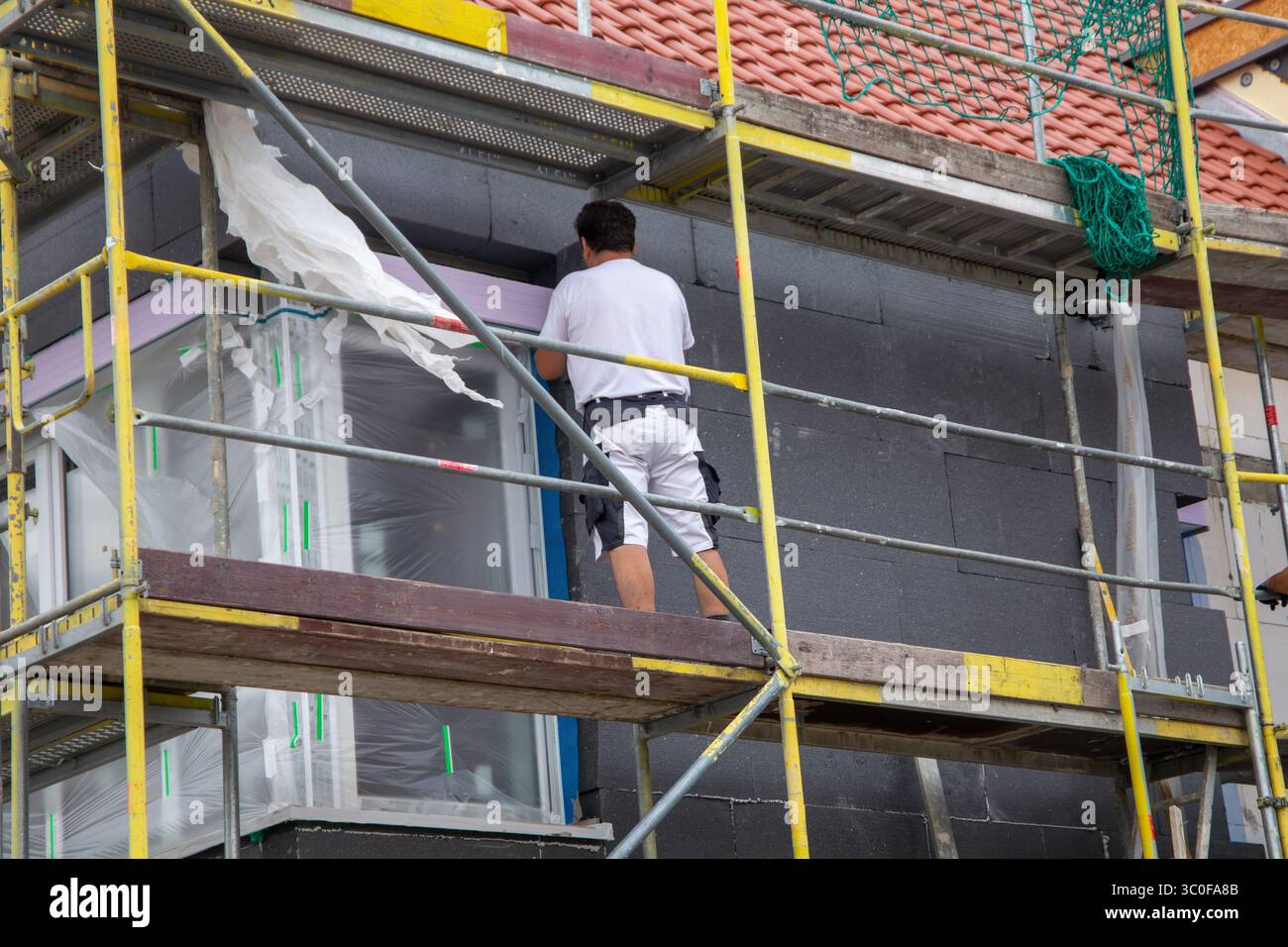 Construction workers insulates house facade Stock Photo
