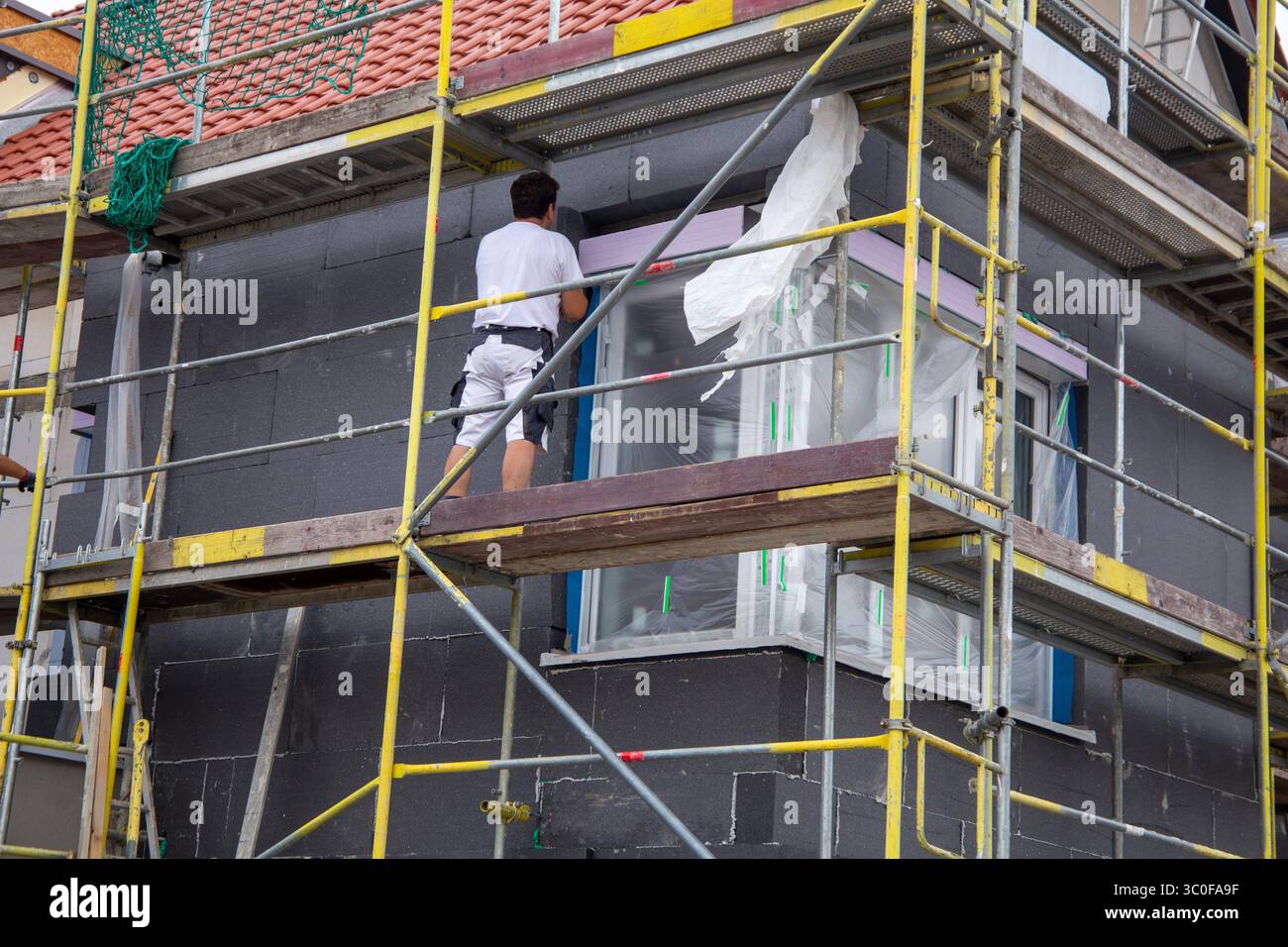 Construction workers insulates house facade Stock Photo