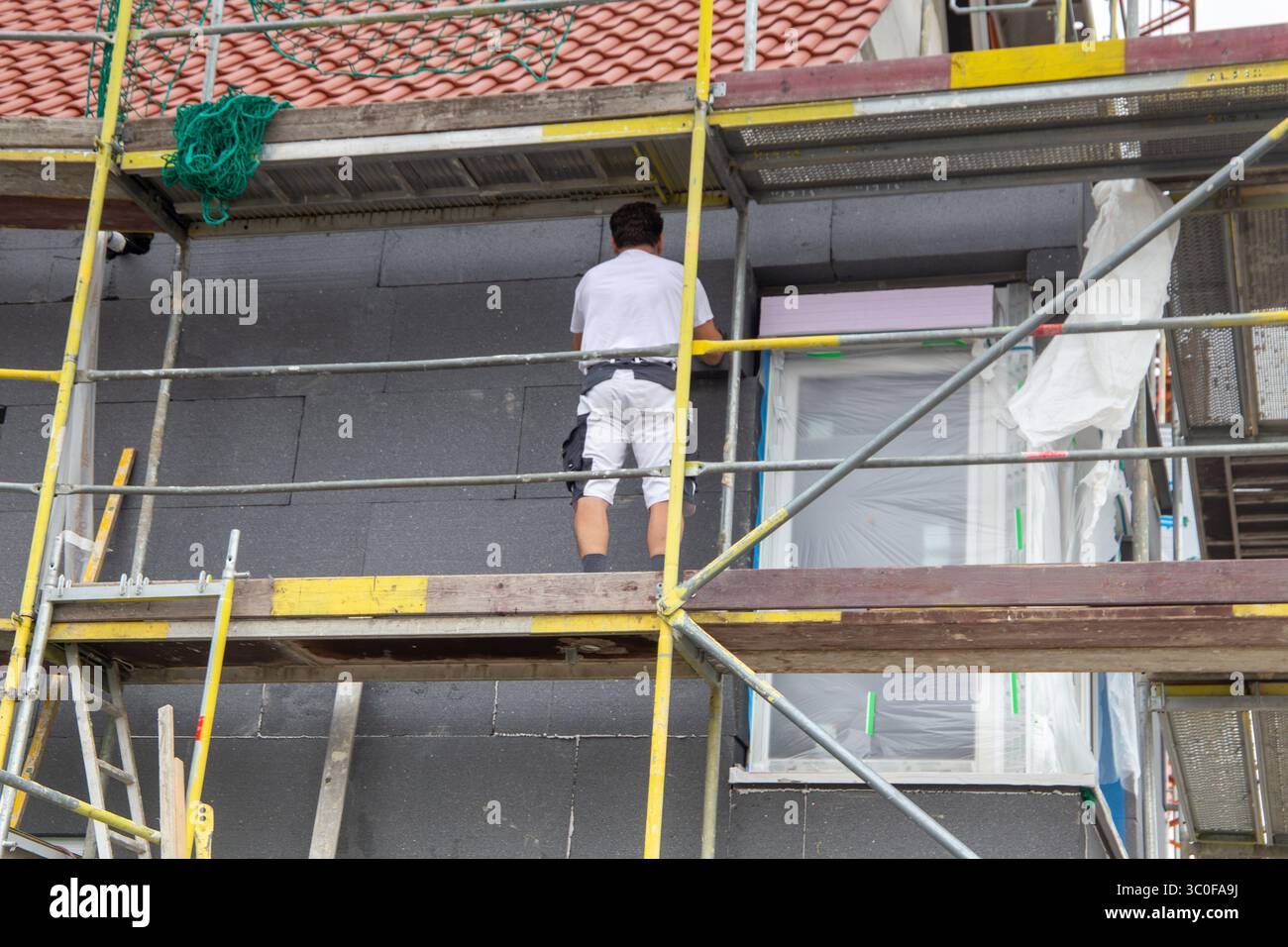 Construction workers insulates house facade Stock Photo