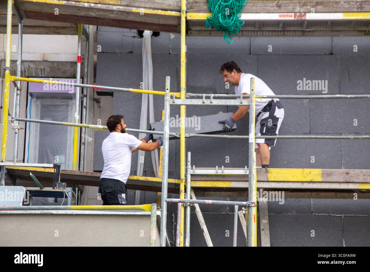 Construction workers insulates house facade Stock Photo