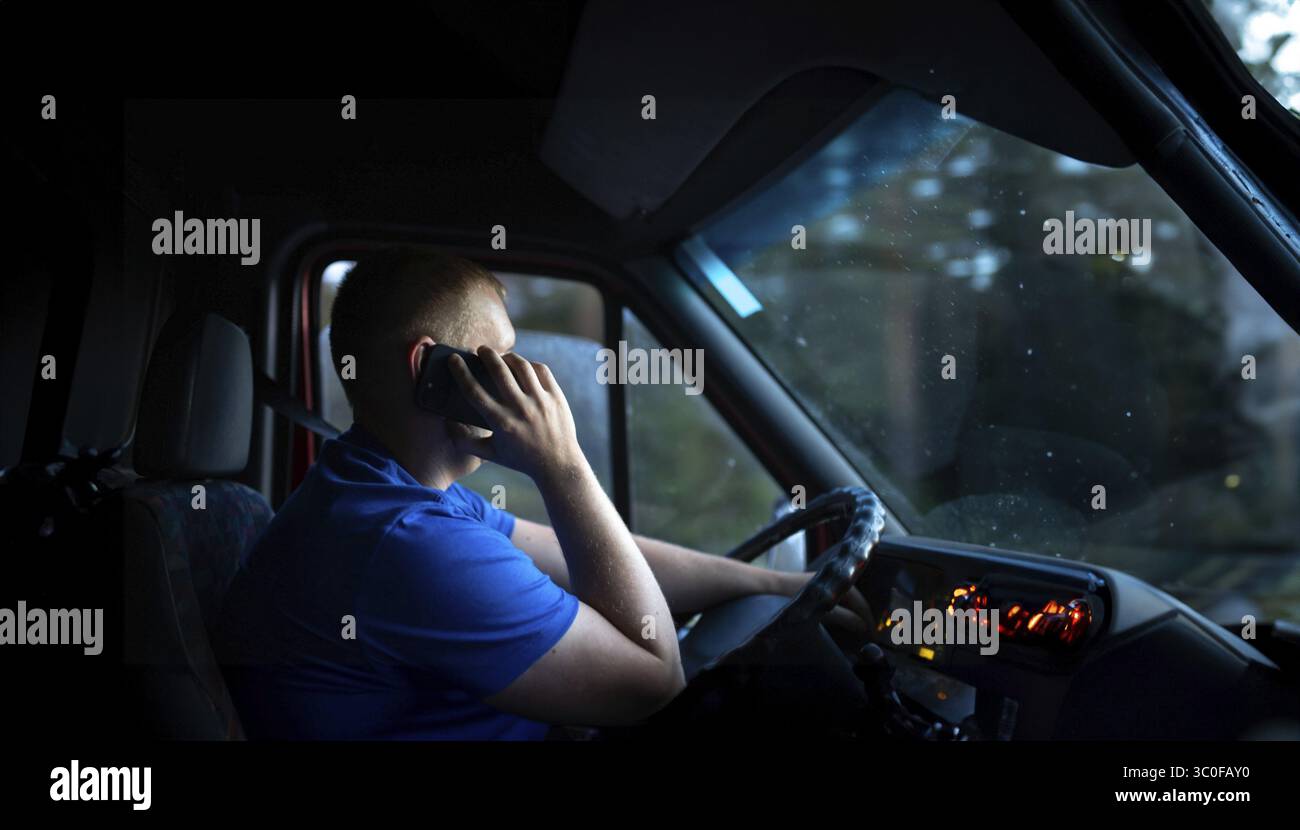 Man on phone while driving van at night, dimly lit interior Stock Photo