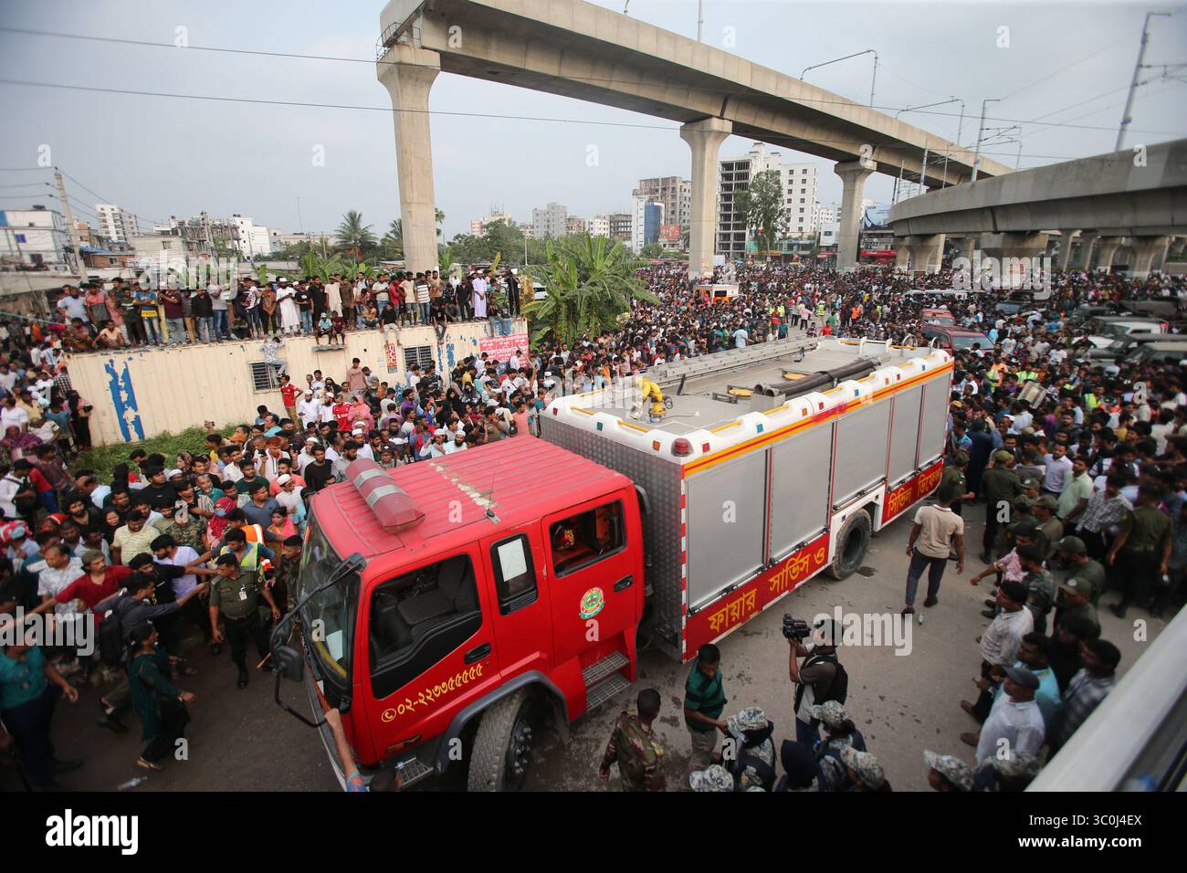 People crowd a street as fire fighting trucks remain on standby outside ...