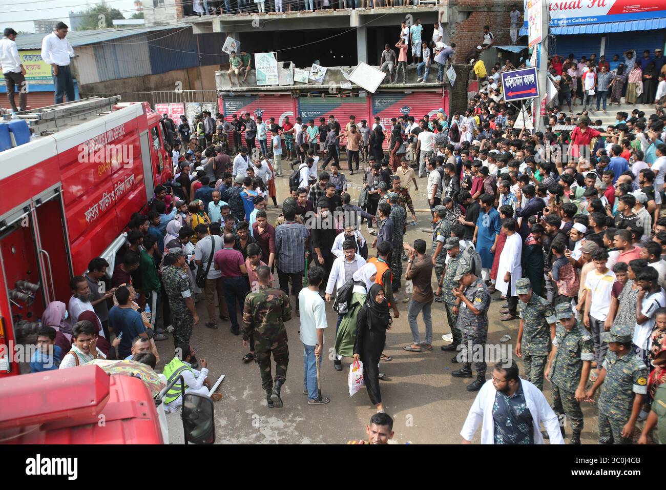 People crowd a street as fire fighting trucks remain on standby outside ...