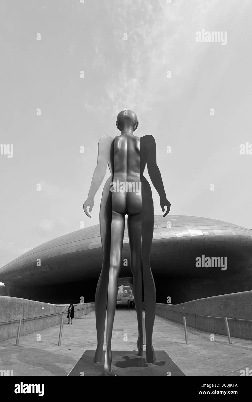 Black and white photo of a modern human figure sculpture in front of DDP Dongdaemun Design Plaza, Seoul, South Korea Stock Photo