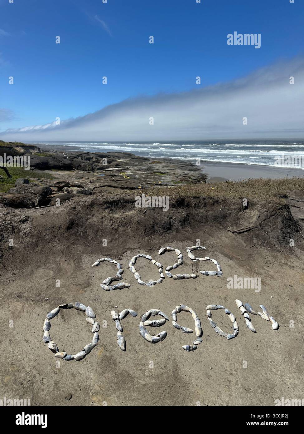 The words '2025 Oregon' written in shells in the sand on the Oregon coast in Yachats on a summer day. - Smartphone Captured Stock Image