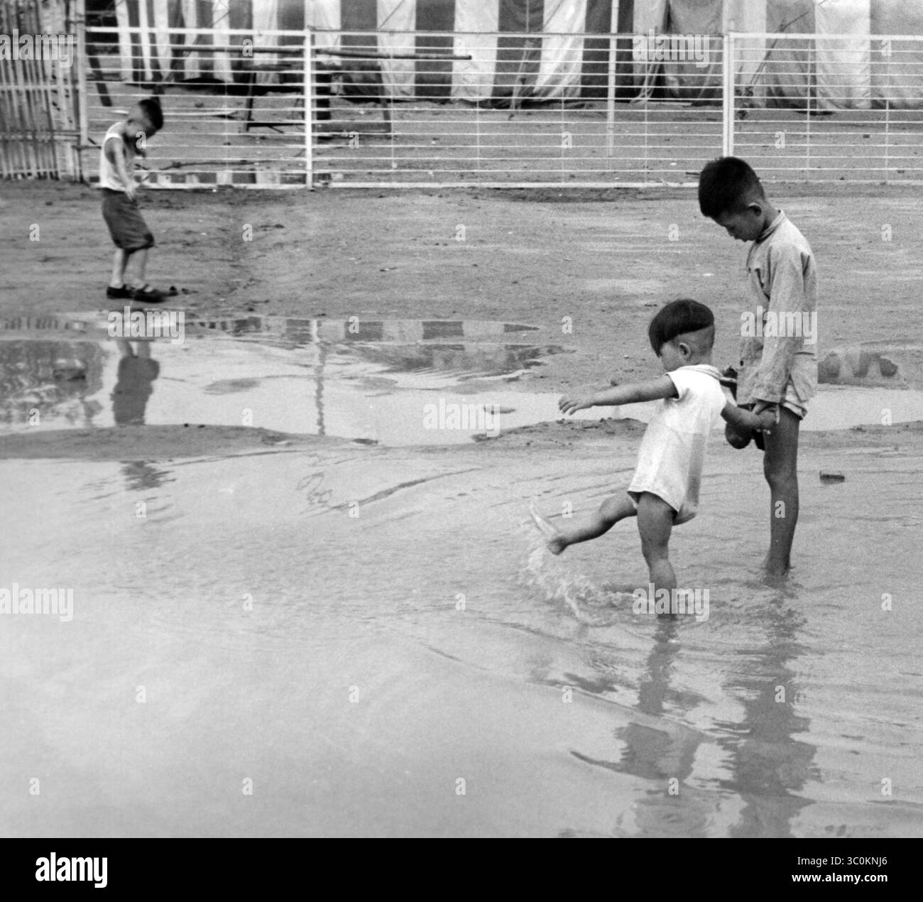 Near the street, children playing in the puddle. China, 1961 (Credit ...