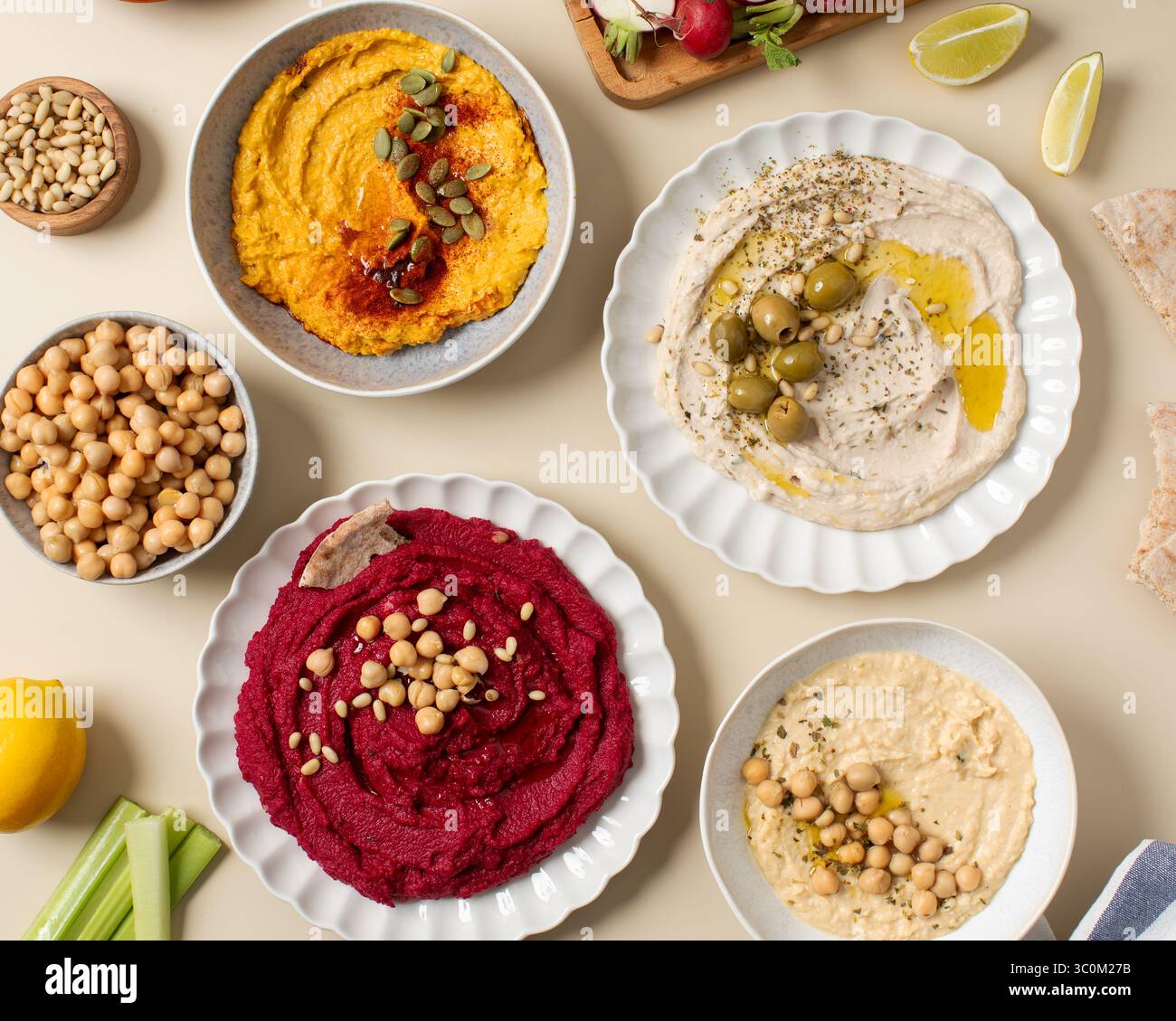 Different types of hummus in bowls and plates. Beetroot, pumpkin ...