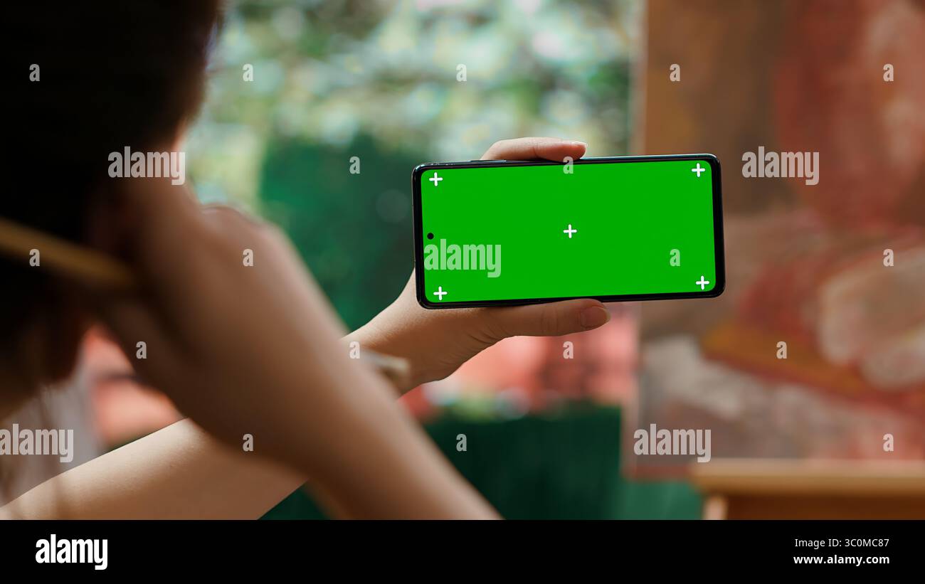 Female artist holding device with green screen in art and craft atelier ...