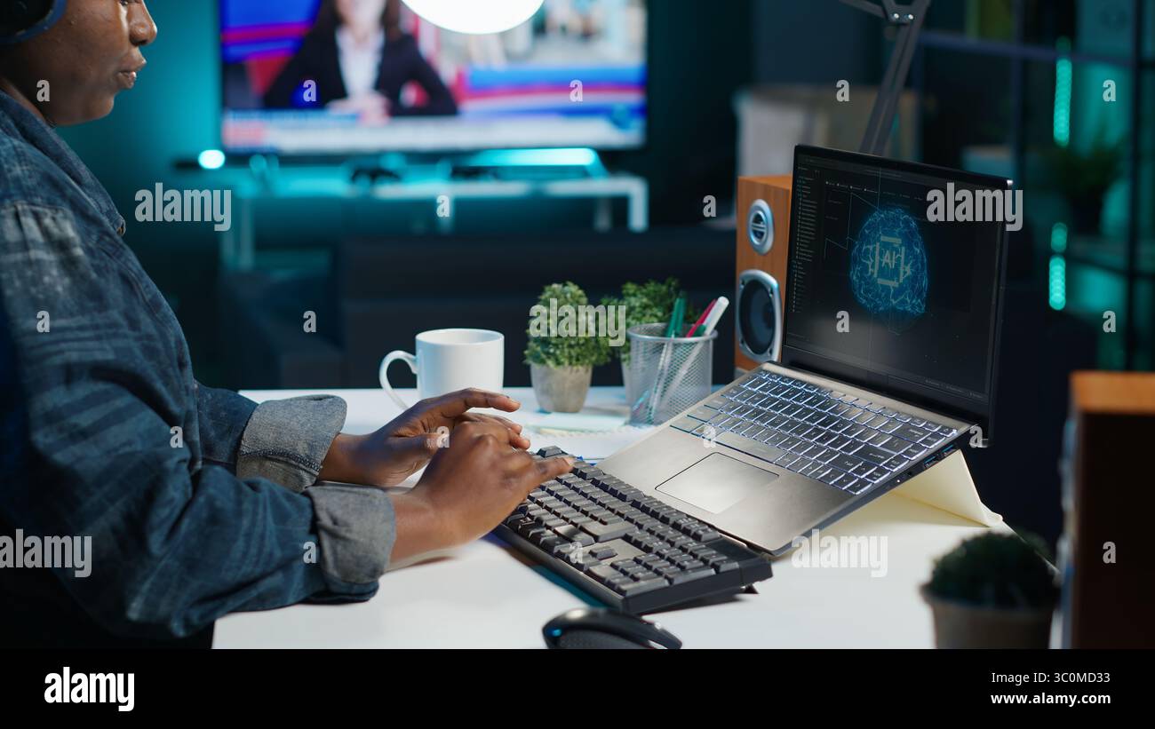 Data scientist using laptop, updating artificial intelligence machine learning algorithms, writing code scripts. Teleworking IT specialist in apartment office uses programming to upgrade AI, camera A Stock Photo