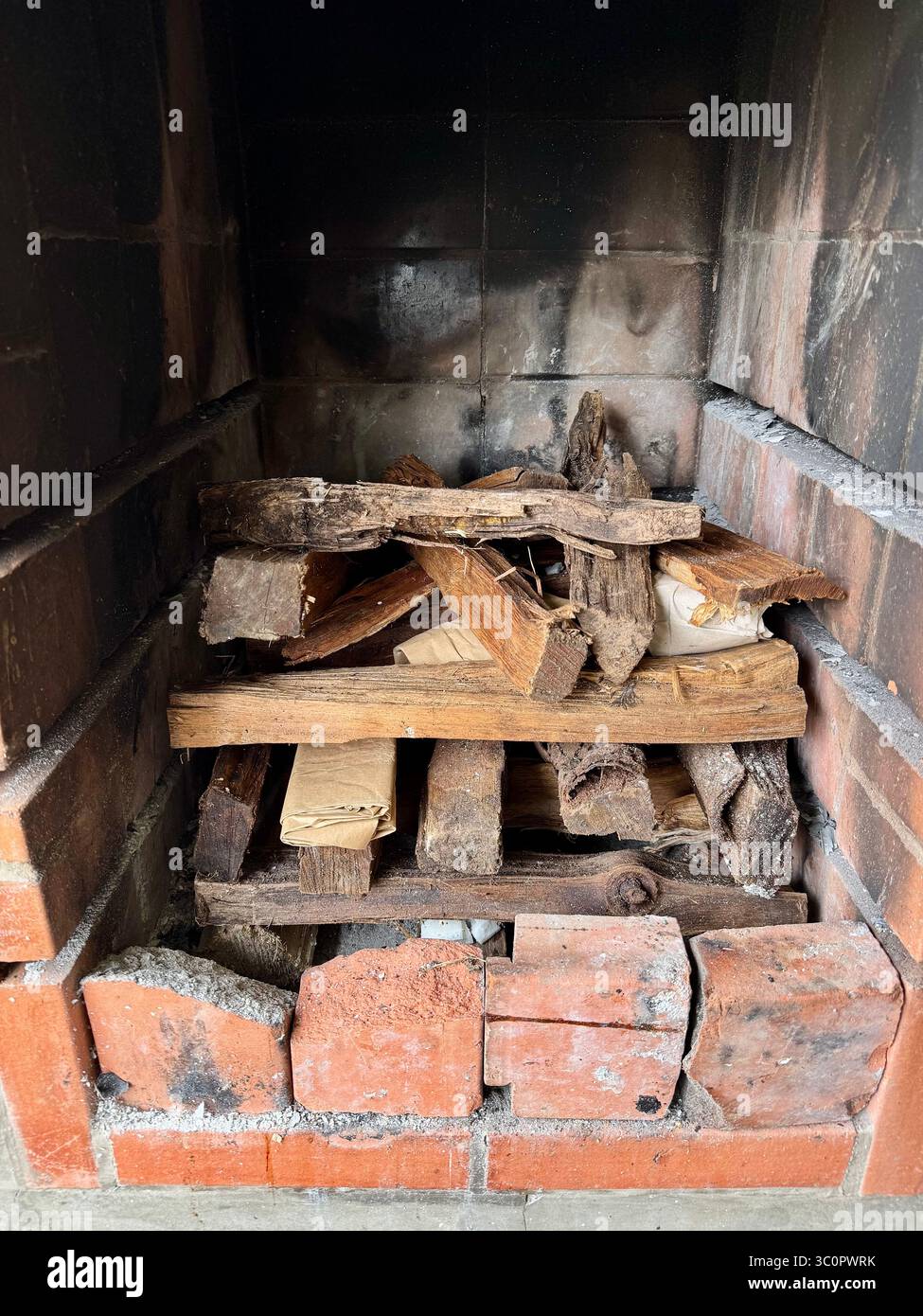 Stacked firewood and kindling prepared in a brick barbecue pit for lighting. - Smartphone Captured Stock Image