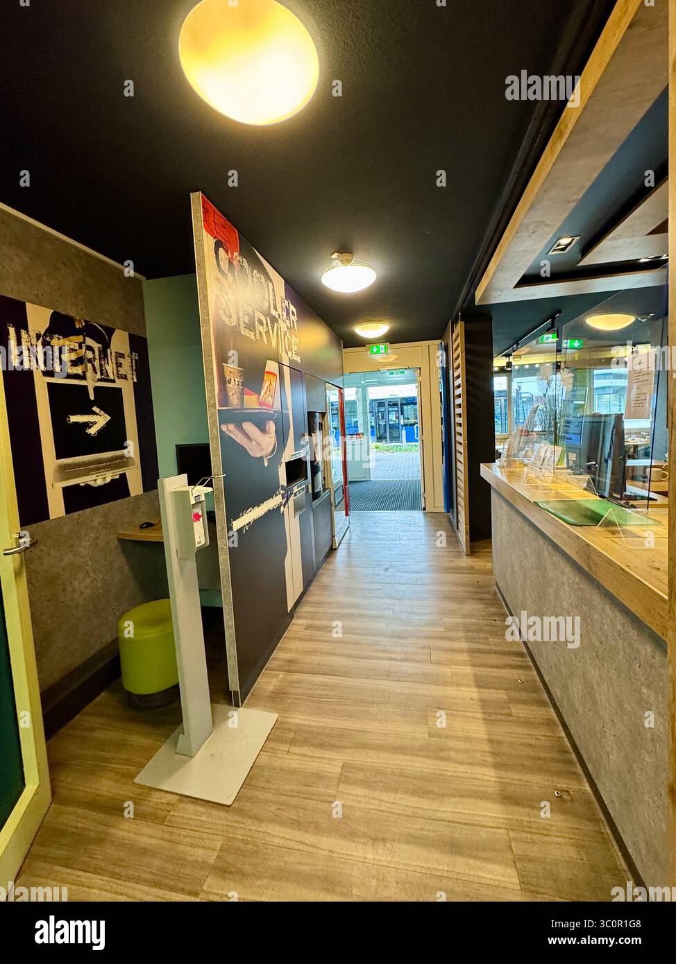 Reception and lobby area of Ibis Budget Hotel in Lübeck, Germany, featuring a modern self-service check-in and internet station. - Smartphone Captured Stock Image