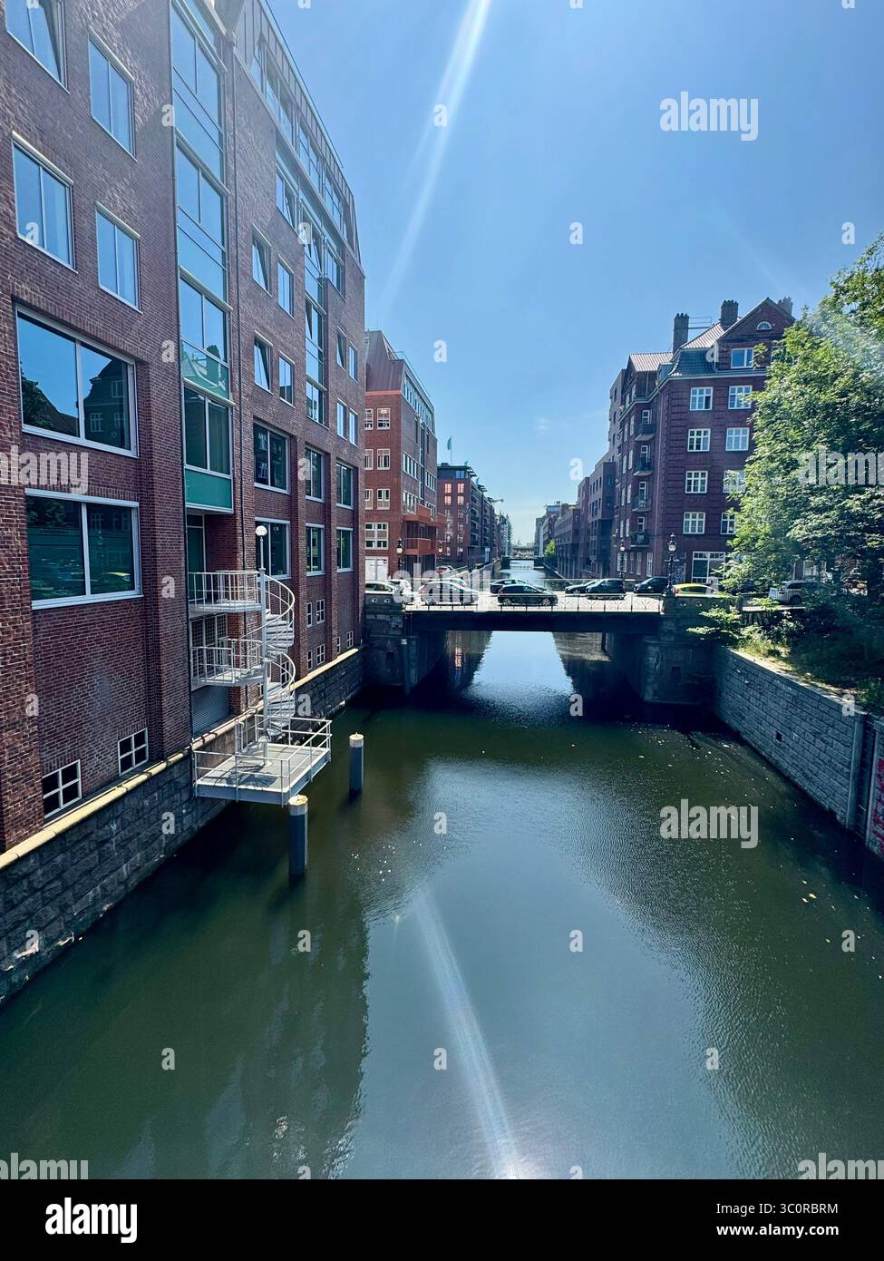 Sunny day view of a canal with a bridge surrounded by brick buildings in Hamburg, Germany. - Smartphone Captured Stock Image