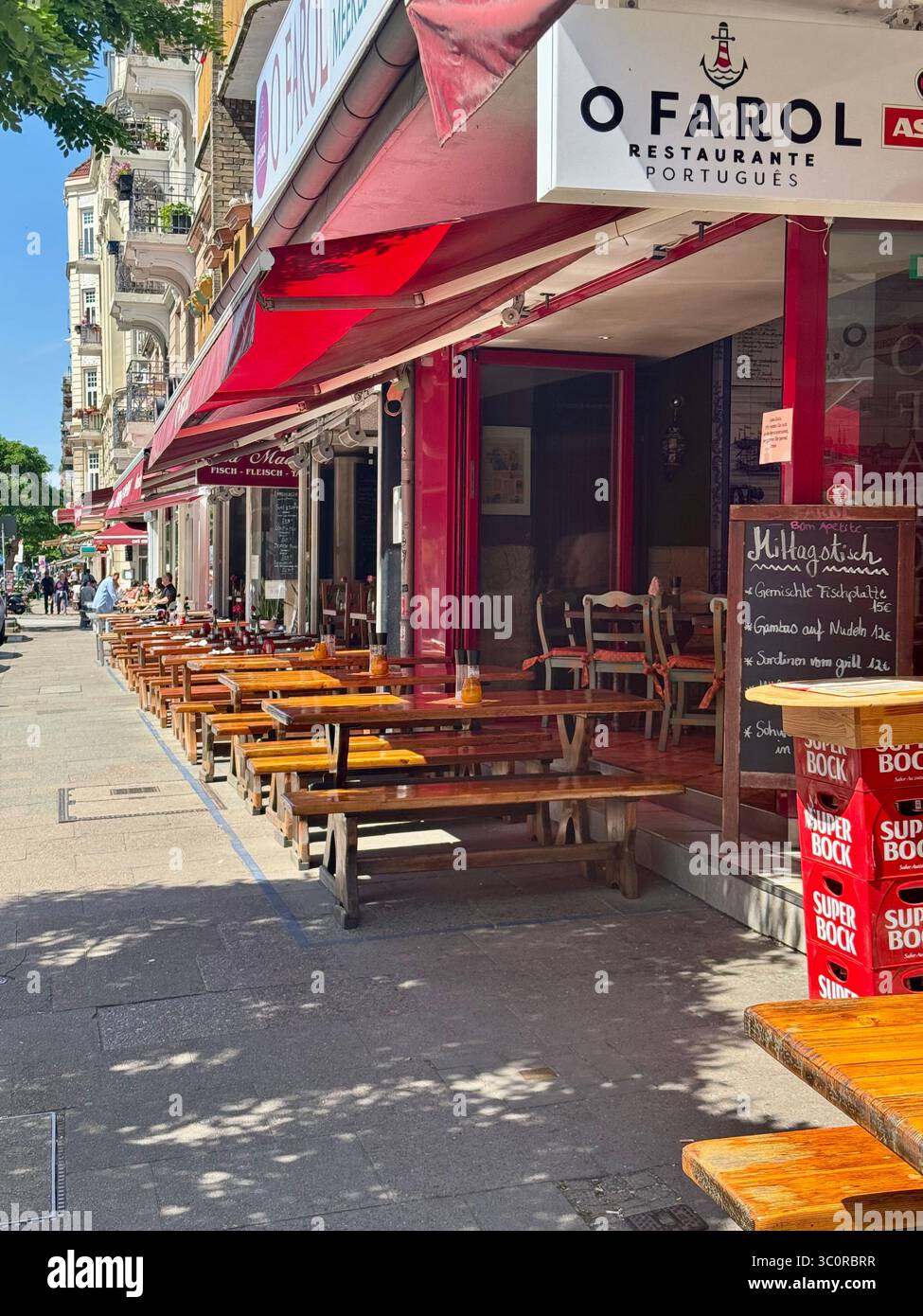 Street view of O Farol Portuguese restaurant with outdoor seating on a sunny day in Hamburg, Germany. - Smartphone Captured Stock Image