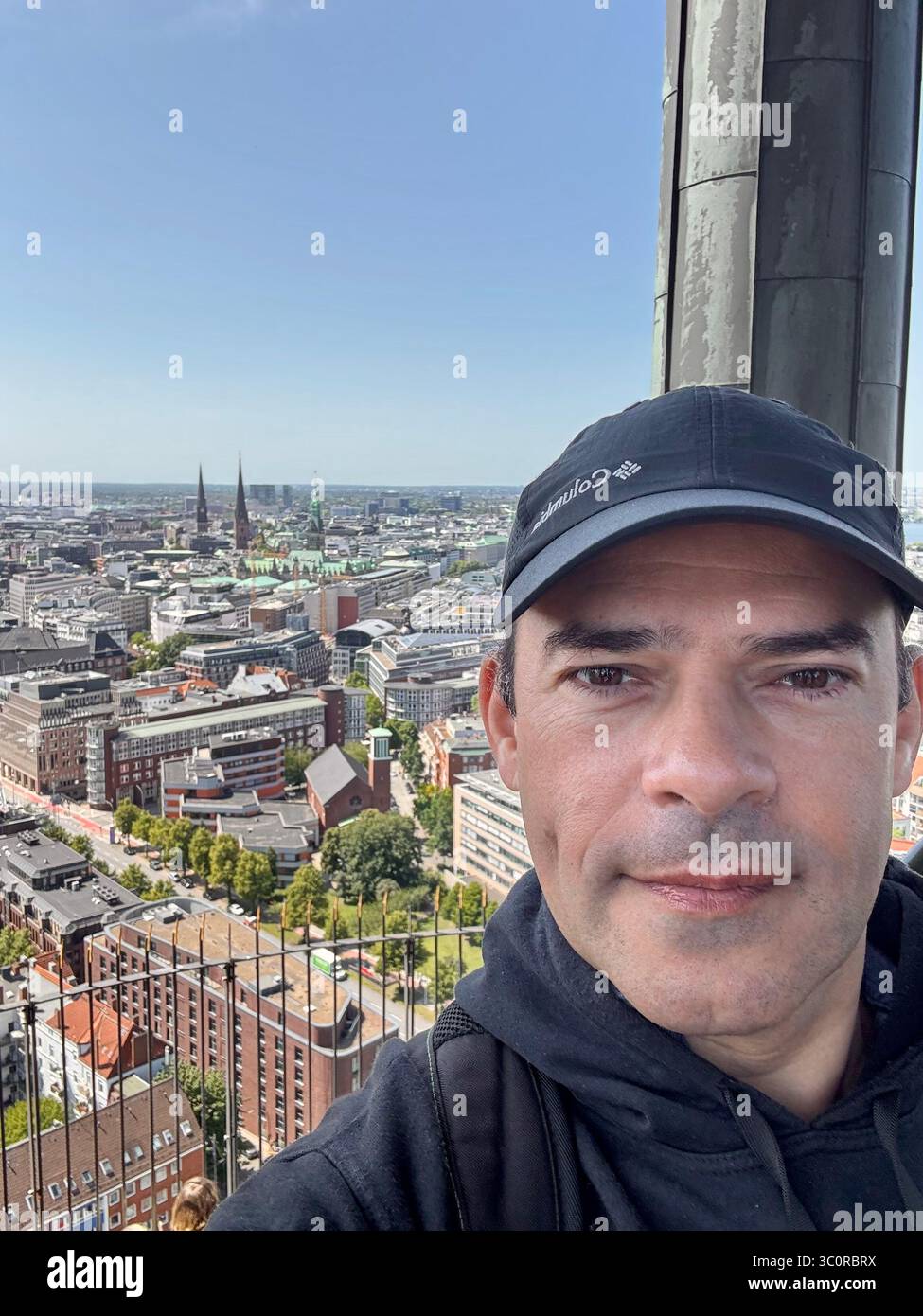A captivating view of Hamburg's skyline at sunset, showcasing the iconic Elbphilharmonie concert hall, the historic St. Michael's Church, and the bust - Smartphone Captured Stock Image