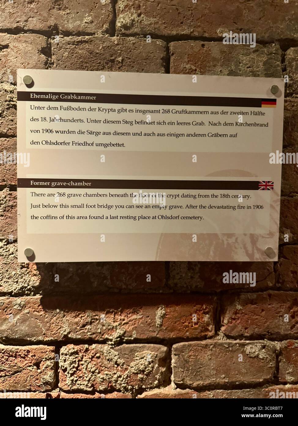 At St Michel church. Historical information plaque about former grave chambers displayed on a brick wall in Hamburg, Germany. - Smartphone Captured Stock Image