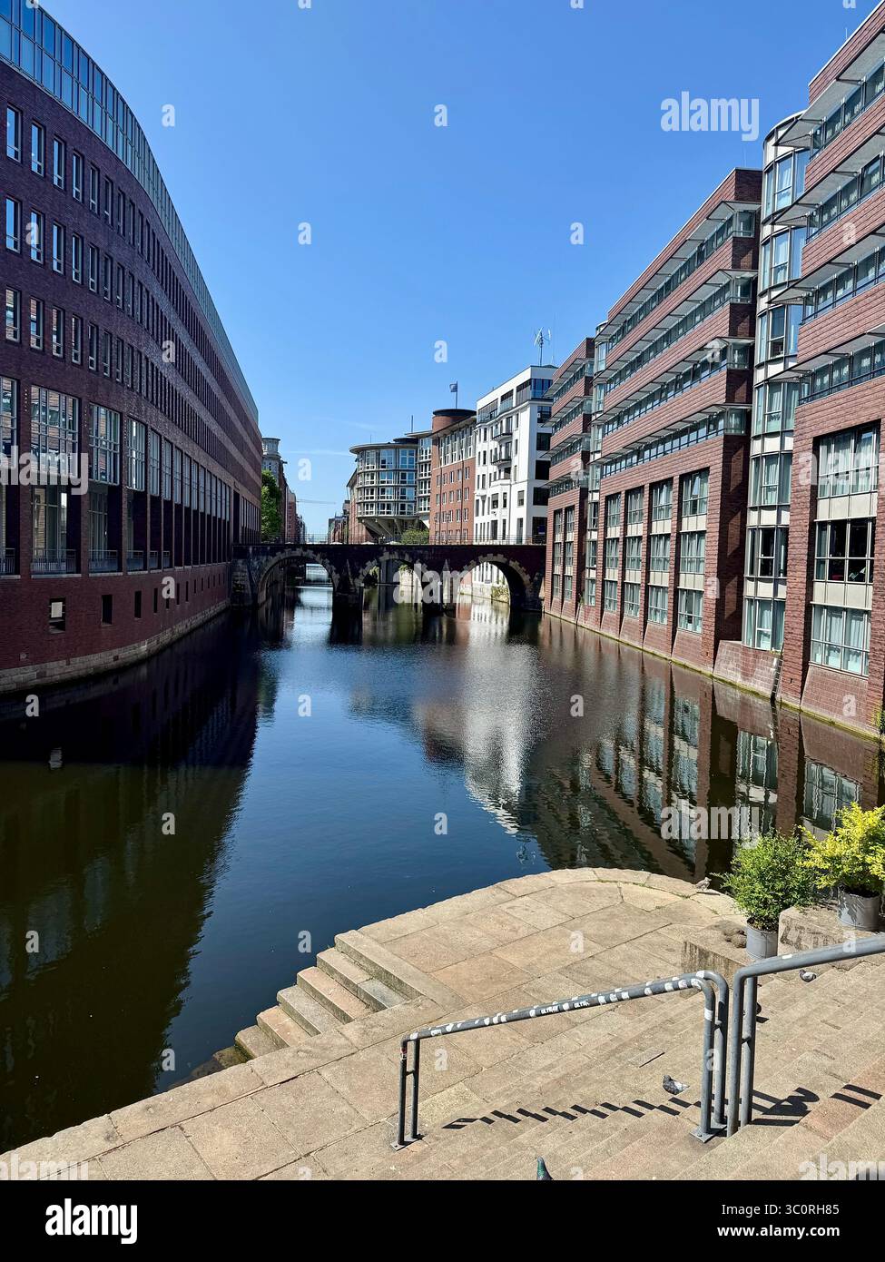 Modern canal buildings in the Kontorhaus district of Hamburg, Germany, with reflections on a sunny day. - Smartphone Captured Stock Image