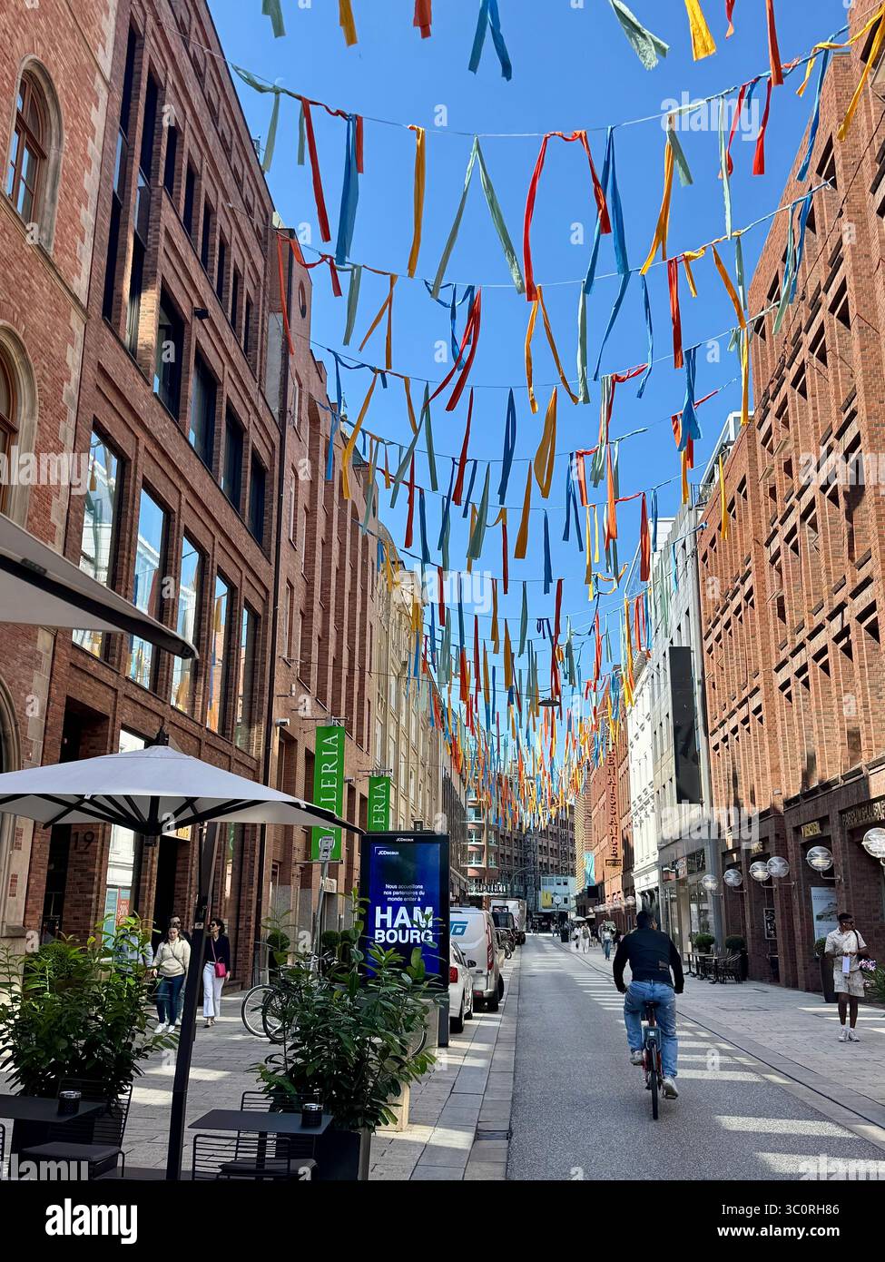 Colorful decorated street with people walking and cycling in Hamburg, Germany, on a sunny day. - Smartphone Captured Stock Image