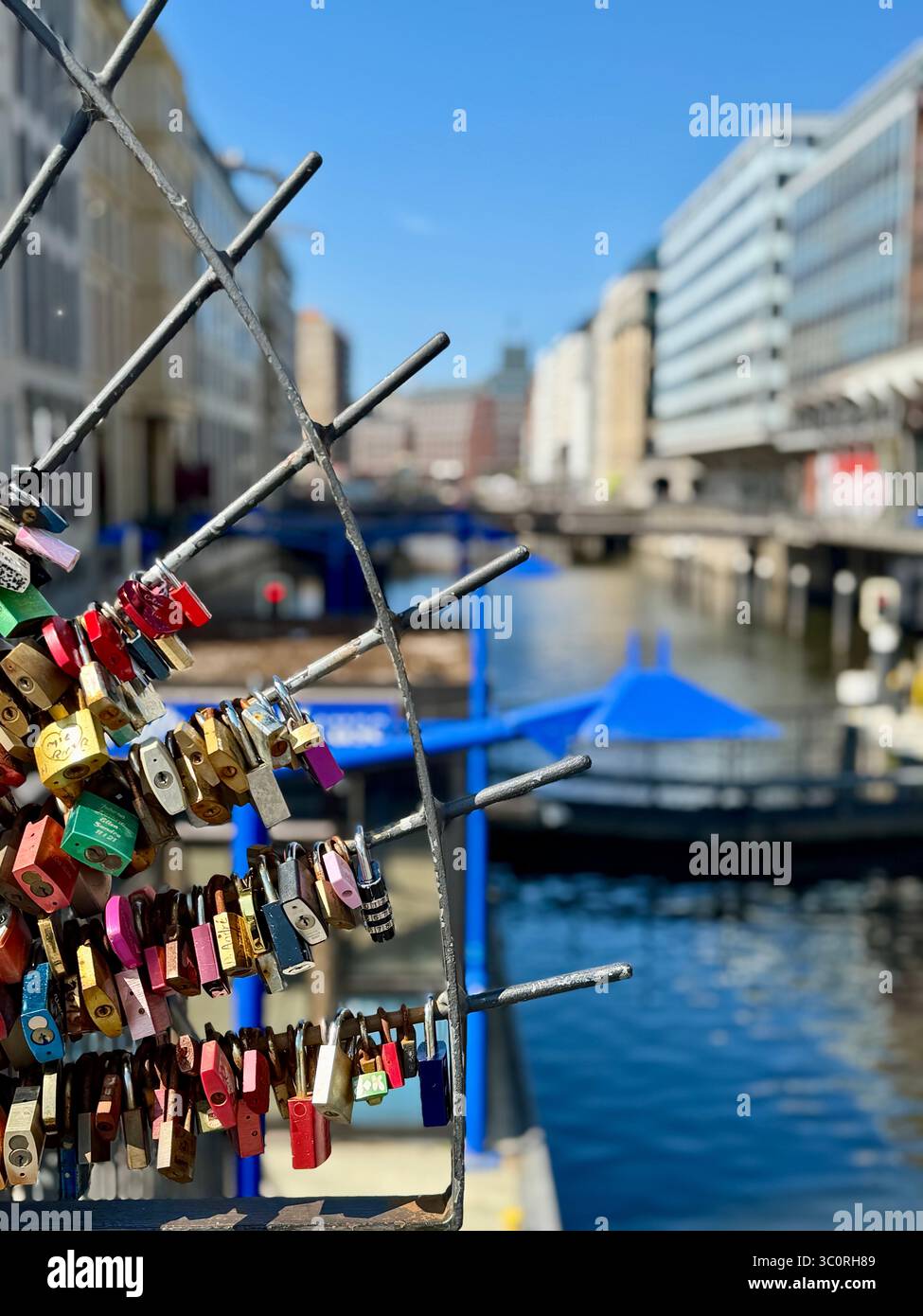 Love locks on a bridge railing over a canal in Hamburg, Germany, symbolizing romantic commitment. - Smartphone Captured Stock Image