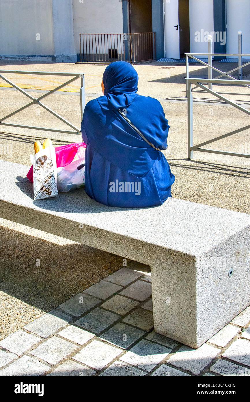 Arab woman resting on stone bench seat - Ozon, Chatellerault, Vienne (86), France. Stock Photo