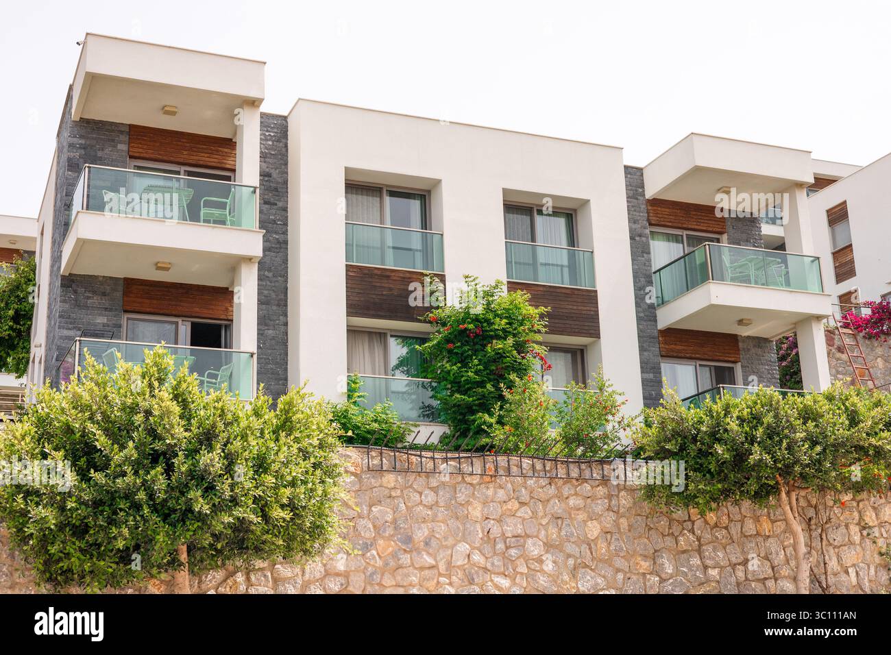 Modern apartment building with balconies and greenery. The structure ...