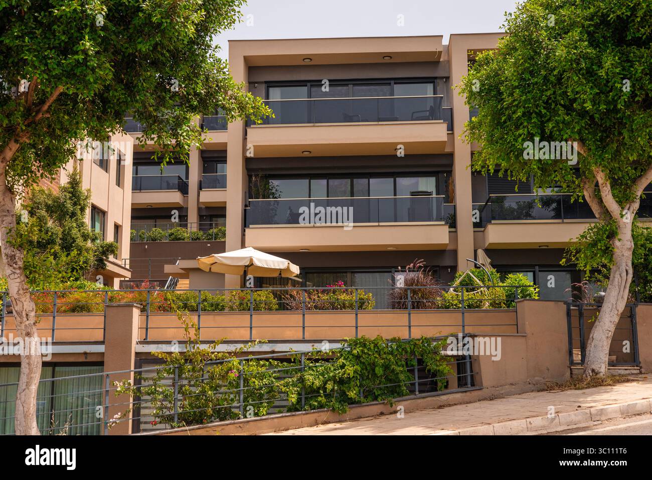 Modern apartment building with large balconies and greenery. The ...