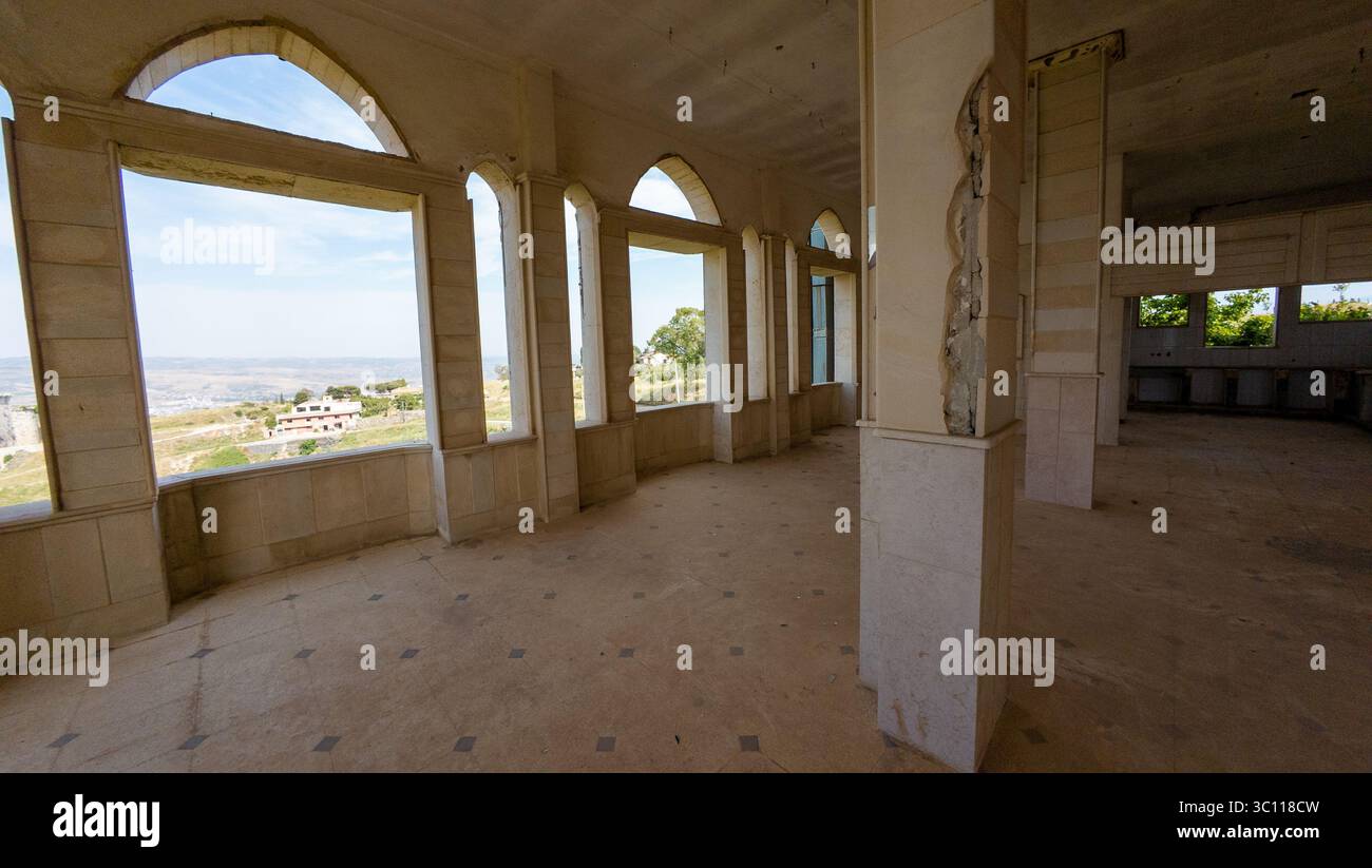 An empty, spacious interior with large arched windows offering a ...