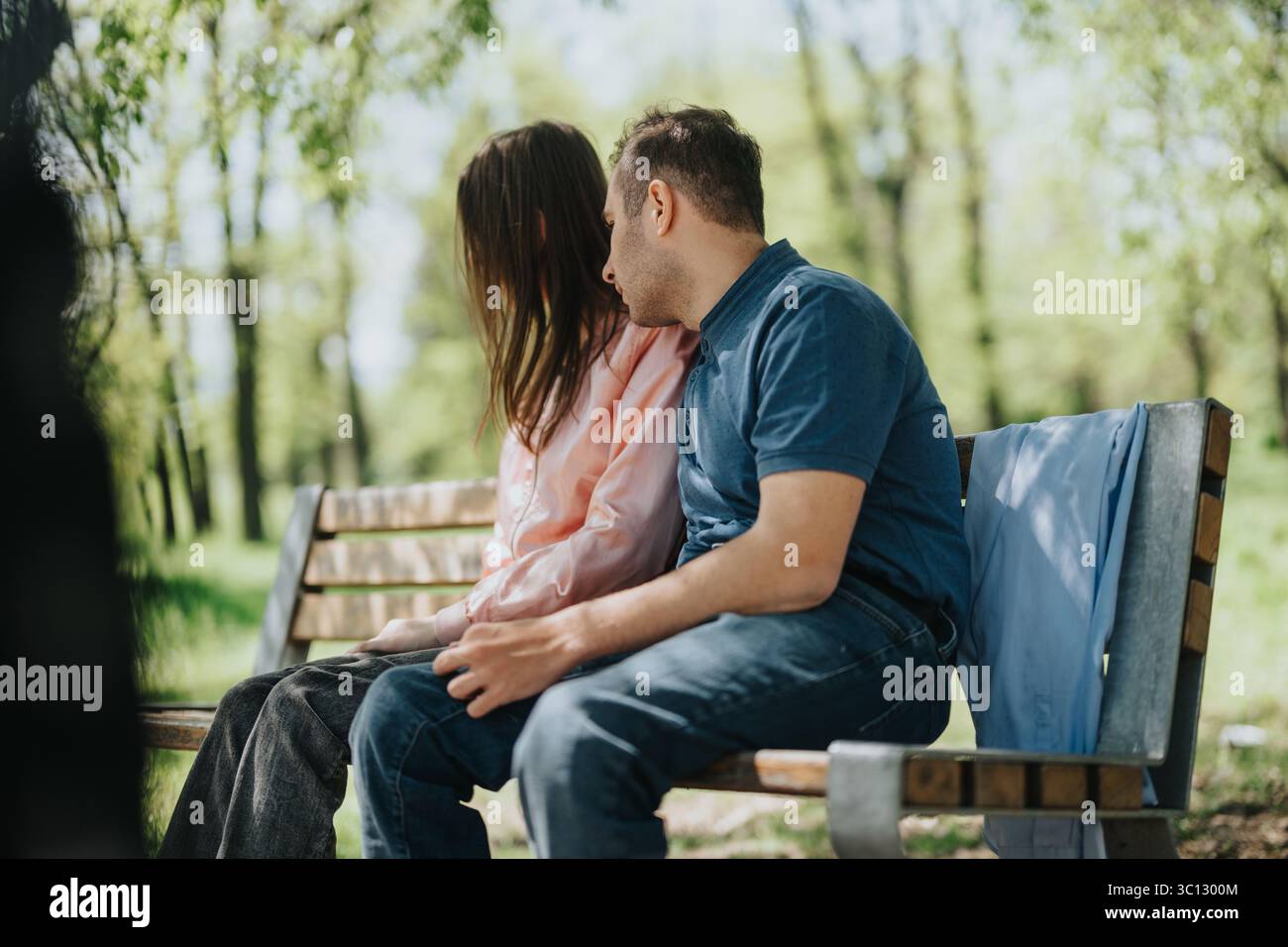 Couple sitting on a park bench sharing a tender moment Stock Photo - Alamy