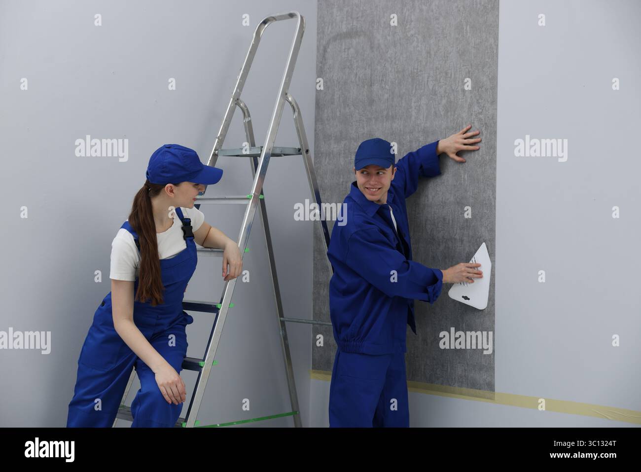 Worker smoothing wallpaper with tool in room Stock Photo