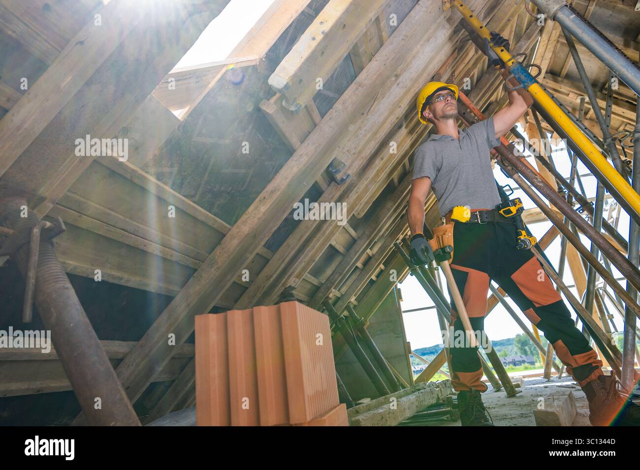 A construction worker uses a lifting device to elevate wooden materials ...