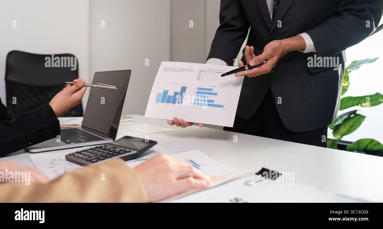 Business Team Collaborates on Data Analysis with Graphs in Modern Office Setting Stock Photo