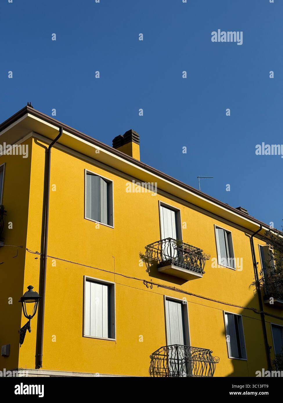 Yellow building contrasted against a vivid blue sky at Bordolino, Lake Garda, Italy Stock Photo