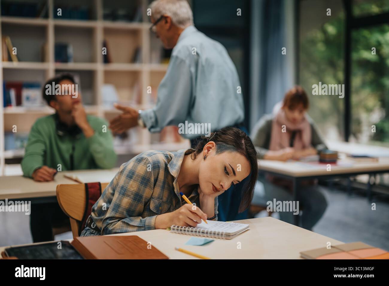 Students engaging with elderly professor in active classroom setting Stock Photo