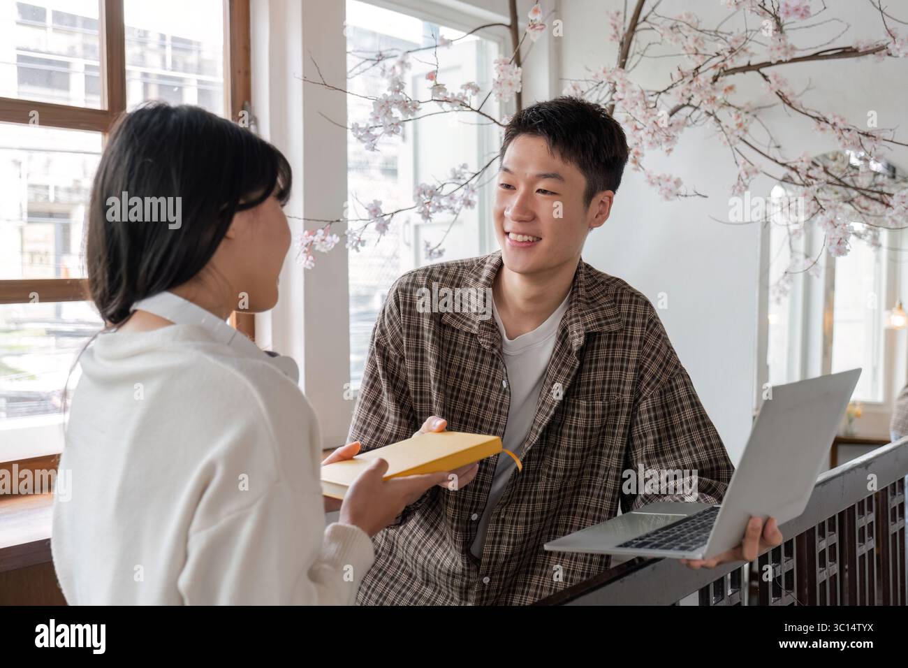 Diverse Group of Students Collaborating on Homework in a Bright, Modern Study Space with Laptops and Books Stock Photo