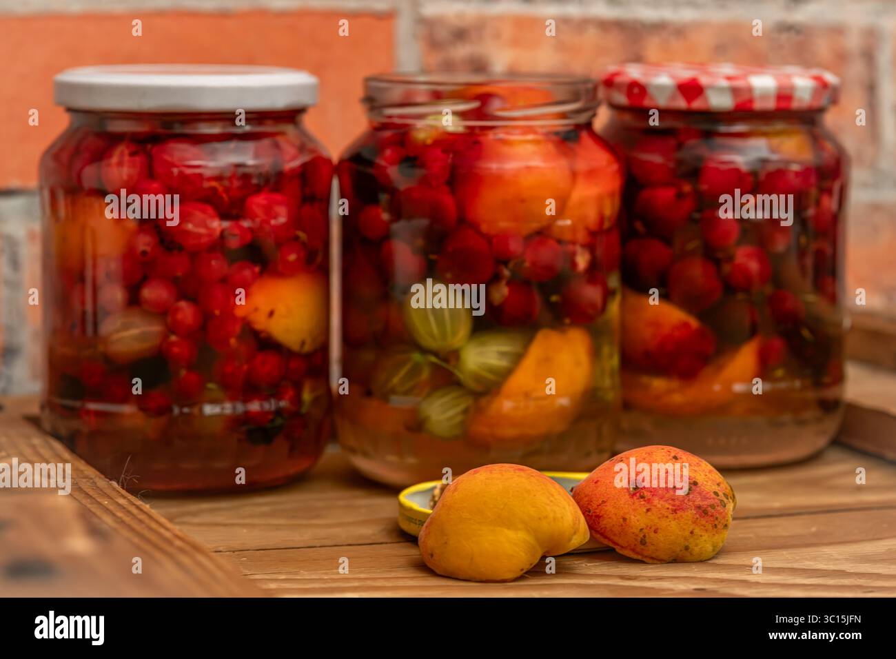 Fruit mix compote on wooden box near red brick old wall Stock Photo