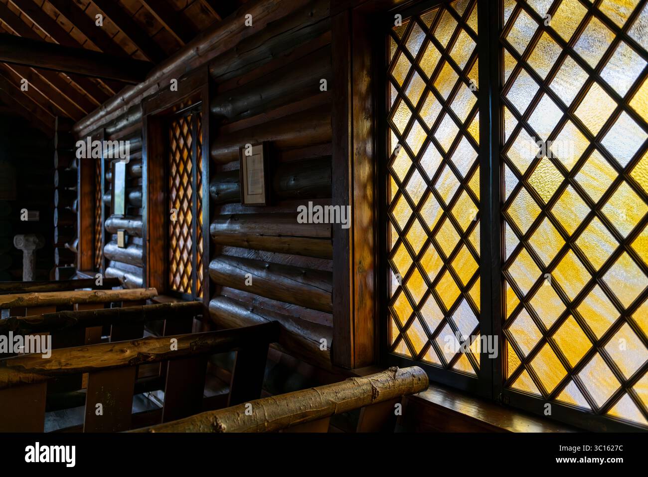 Simple yellow stained glass windows line the log walls of the Chapel of the Transfiguration near Grand Teton National Park, Wyoming, United States Stock Photo