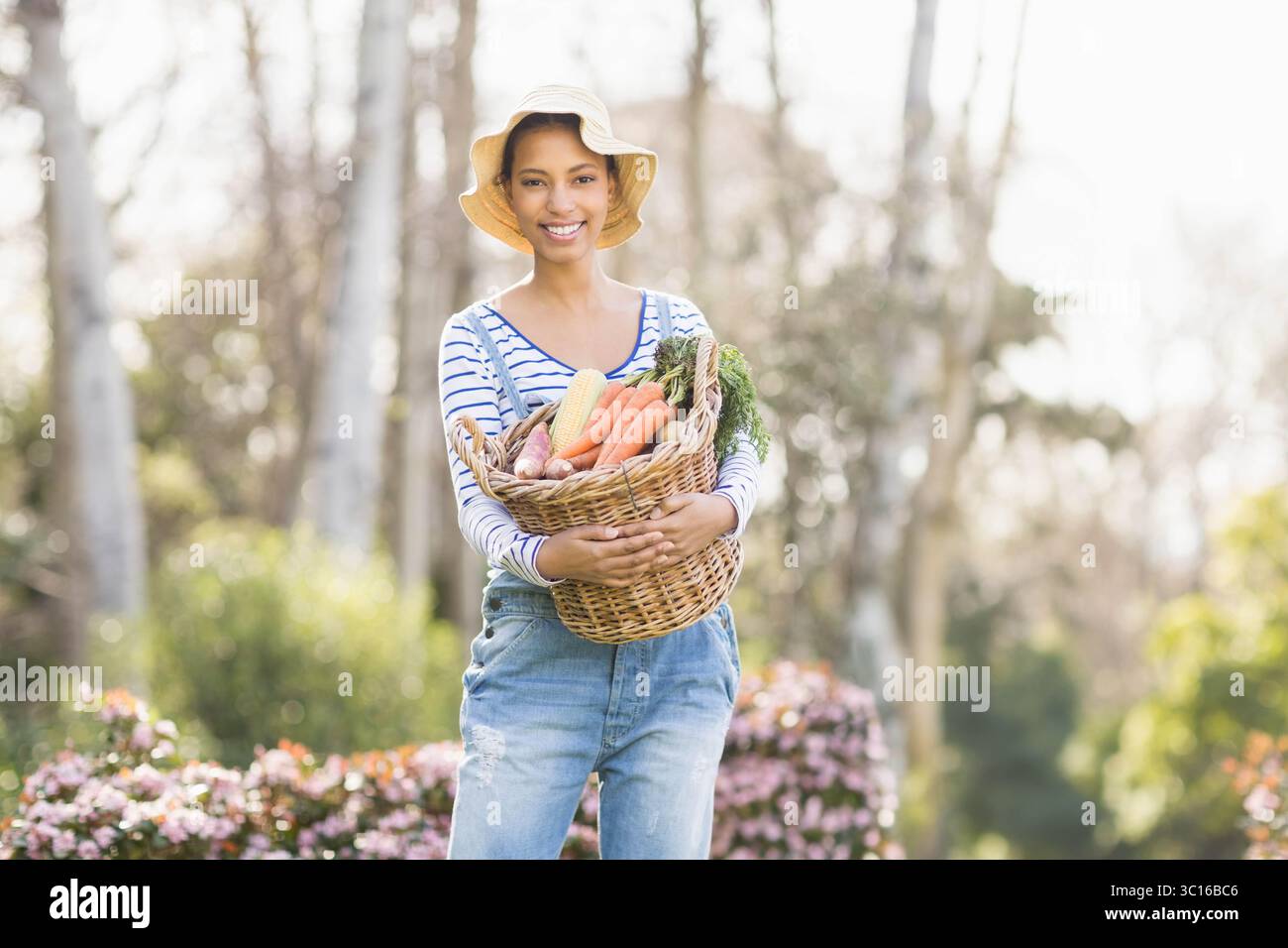 African American woman holding wicker basket of fresh vegetables in ...