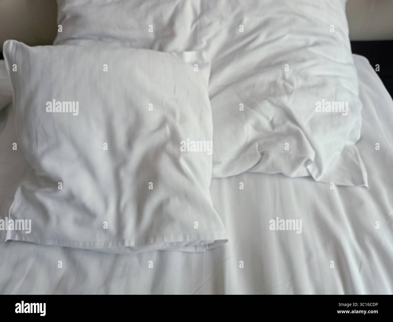 Empty wrinkled white bedding, close up, hotel, white pillows Stock Photo