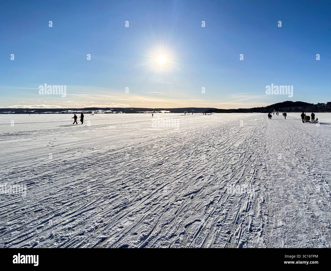 A beautiful winter landscape scene with people walking on snow under a bright sun. - Smartphone Captured Stock Image