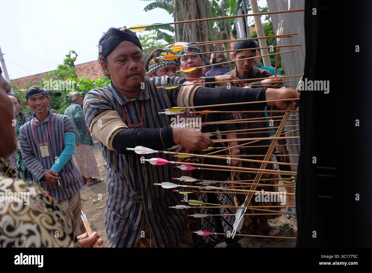 A man pulls out an arrow stuck in the surface of a target during a traditional Javanese archery sport, Jemparingan. Stock Photo