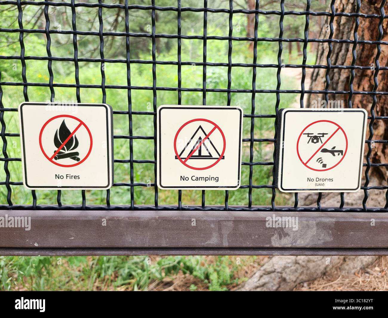 Prohibition signs on a fence: No Fires, No Camping, No Drones (UAV) - Smartphone Captured Stock Image