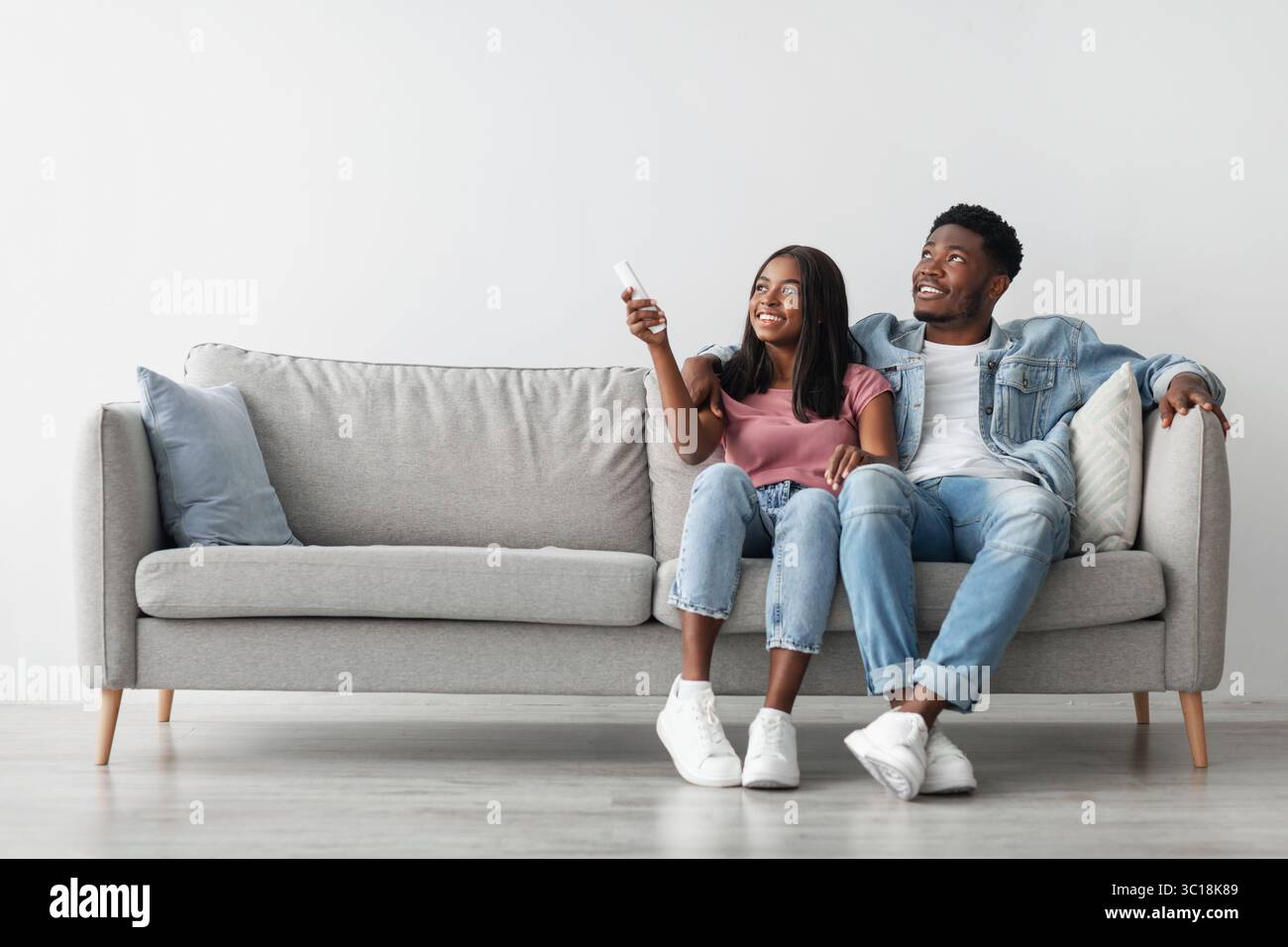 Young black woman switching on air conditioning at her home Stock Photo