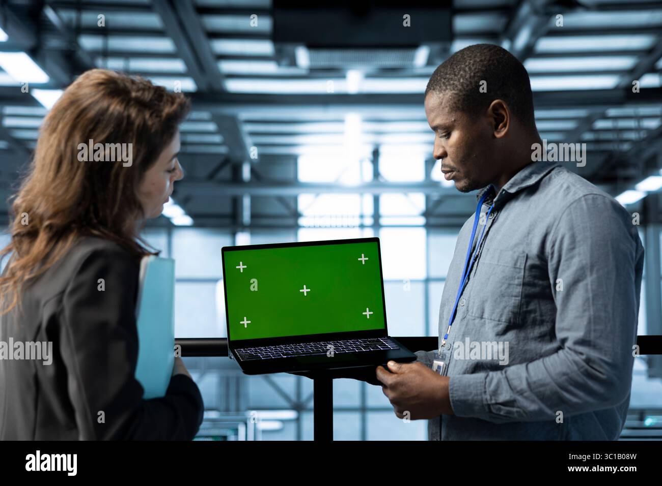 Engineer in data center using green screen laptop, refining server virtualization strategies, configuring cluster nodes, adjusting routing rules, maintaining efficient workflows Stock Photo