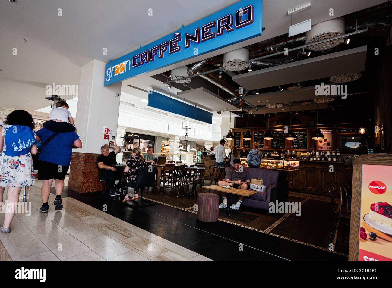 Warsaw, Poland - July 02, 2025: Bright Green Caffè Nero cafe in Warsaw, Poland, with visitors enjoying coffee and a cozy setting. Stock Photo