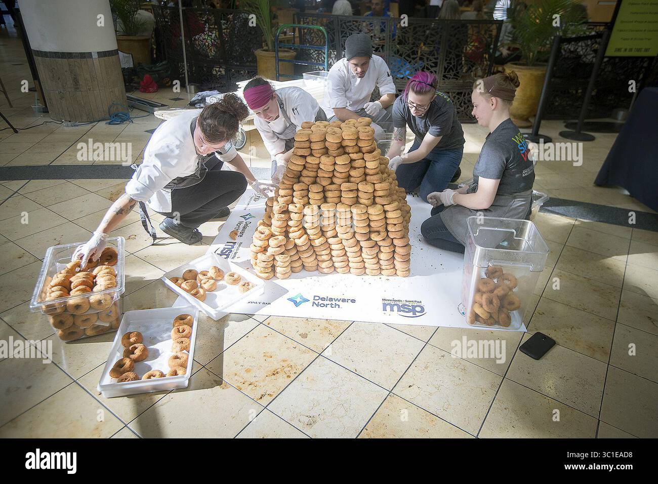 October 17, 2017 - Bloomington, MN, USA - United States - Local award-winning baker Katherine Gerdes, left, and other bakers from left, Natalie Perrin, Armand Osbon, Alyssa Woodard, and Dana Stowell joined forces as they attempted at breaking a world record for the highest doughnut stack at the Minneapolis/St. Paul International Airport, Tuesday, October 17, 2017 in Bloomington, MN. (Credit Image: Elizabeth Flores/Minneapolis Star Tribune/TNS via ZUMA Wire) Stock Photo