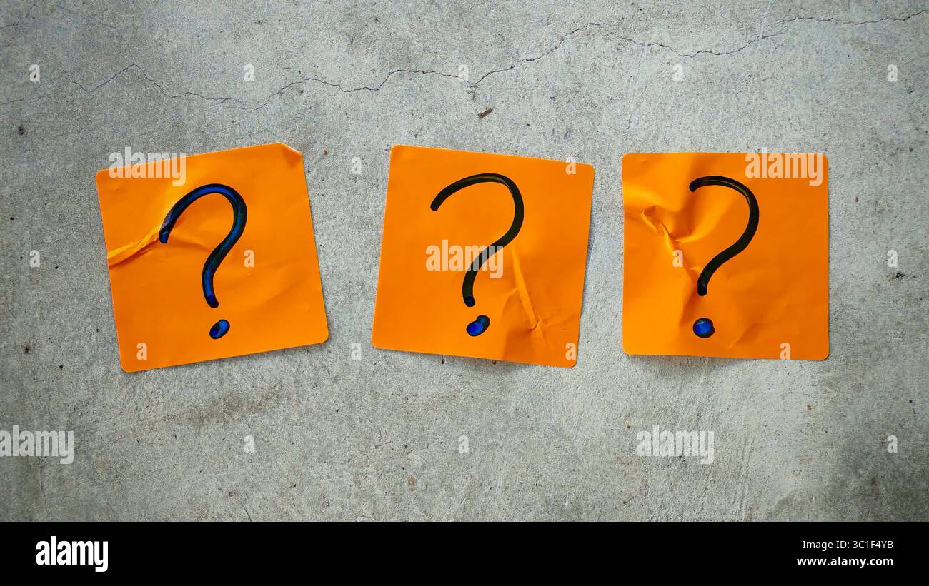 Three Blue Question Marks on Orange Sticky Notes on a Cracked Concrete Background Stock Photo