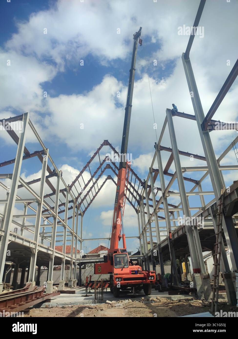 Steel structure construction site with crane and workers, showing the framework of an industrial building under development. - Smartphone Captured Stock Image