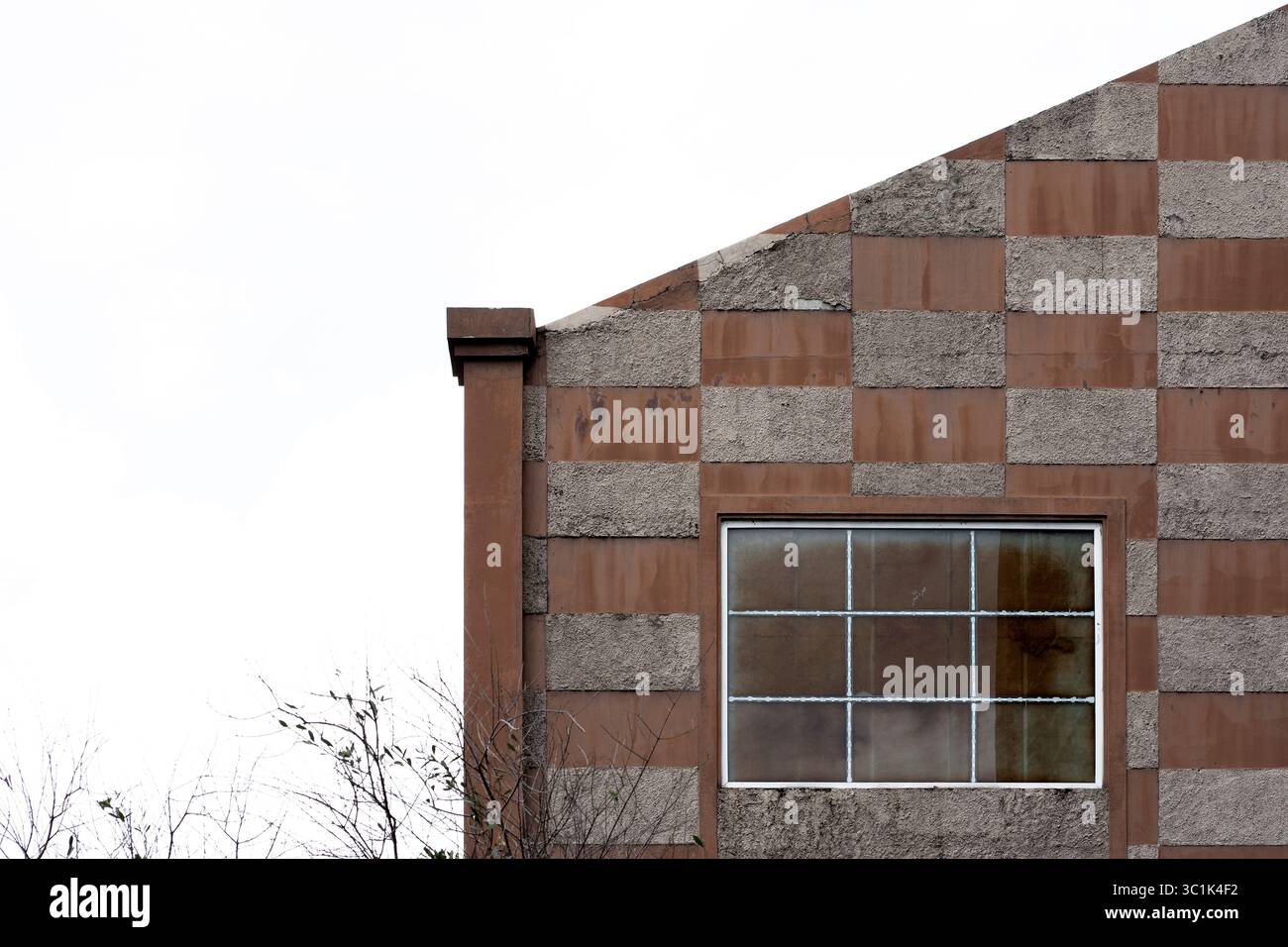 Minimalist architectural detail of a modern building facade with a checkerboard pattern and a window. Abstract background with copy space. Stock Photo