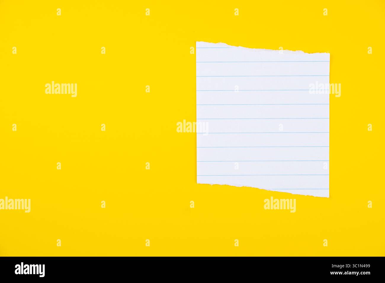 Torn lined notebook paper on vibrant yellow background for notes and creative projects Stock Photo