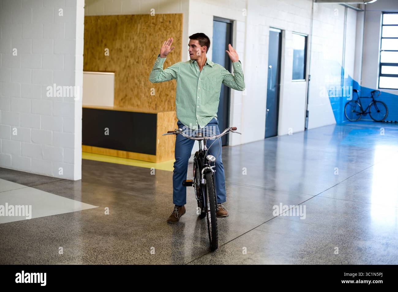 Bicycle rider balancing with hands raised while riding through office ...